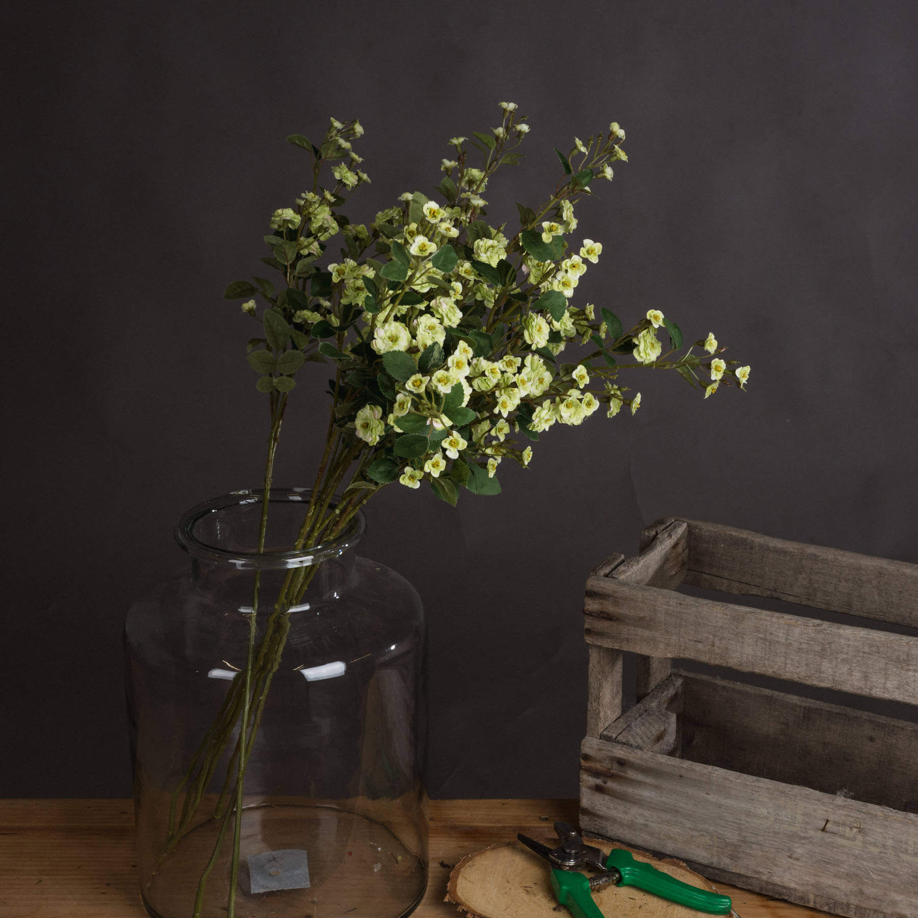 a bold close-up of a wild green meadow rose faux stem against a dark leather bag