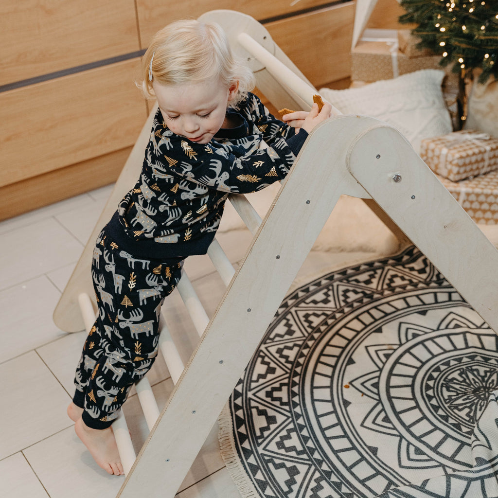 toddler giggling while climbing the foldable montessori triangle in a sunlit playroom
