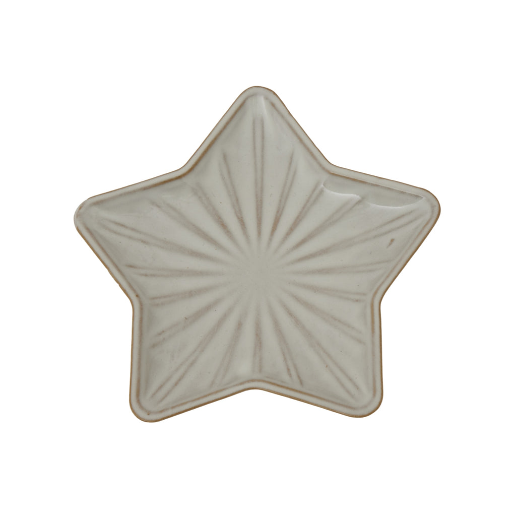 a soft-lit white ceramic star dish casting gentle shadows on a cozy bedside table