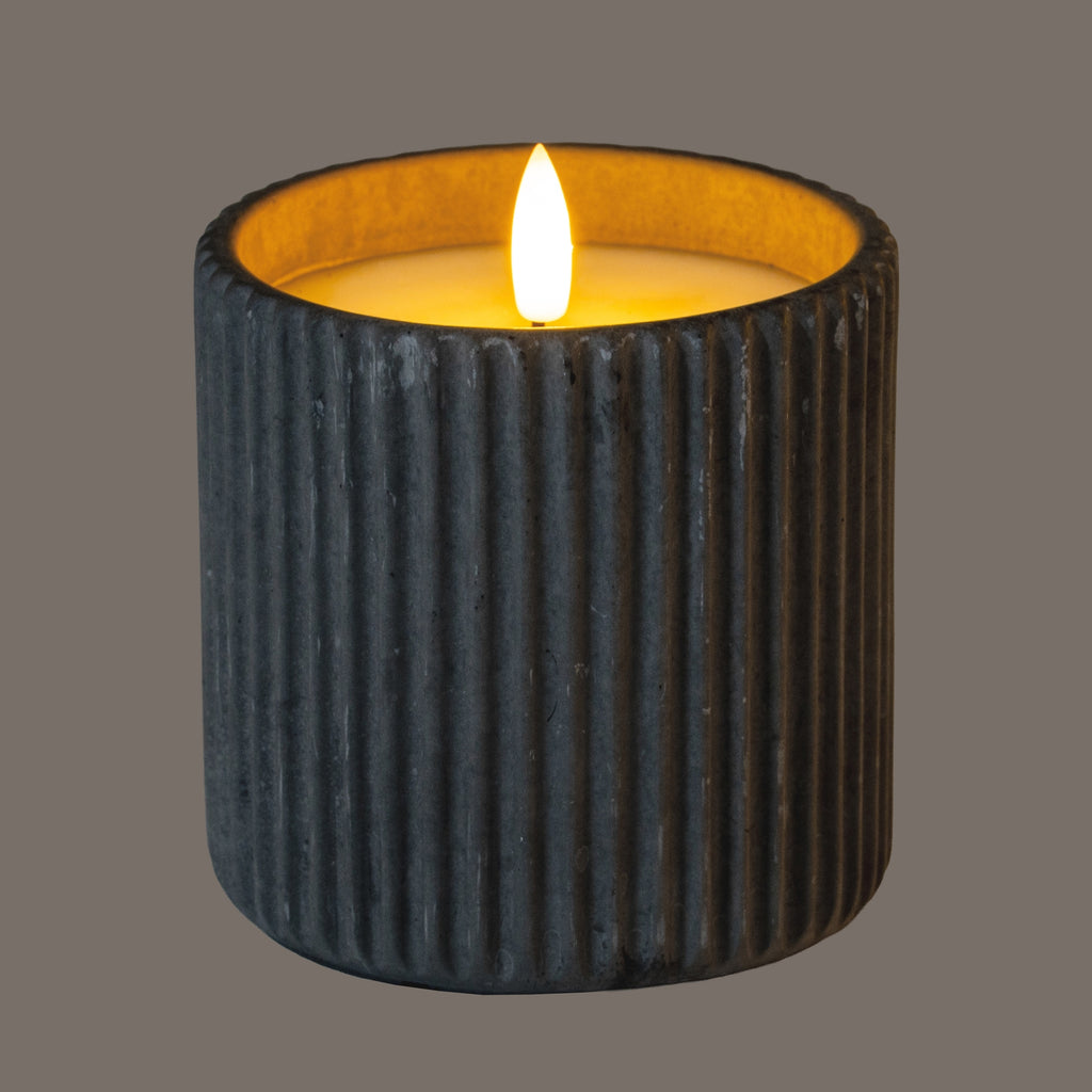 a soft grey ribbed led candle glowing warmly in a cozy, inviting home setting