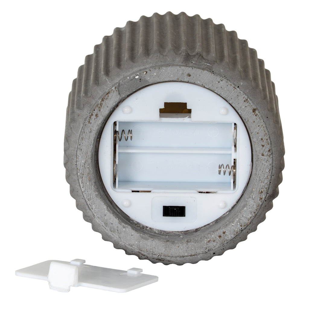 large grey ribbed led candle glowing on a kitchen countertop next to a recipe book