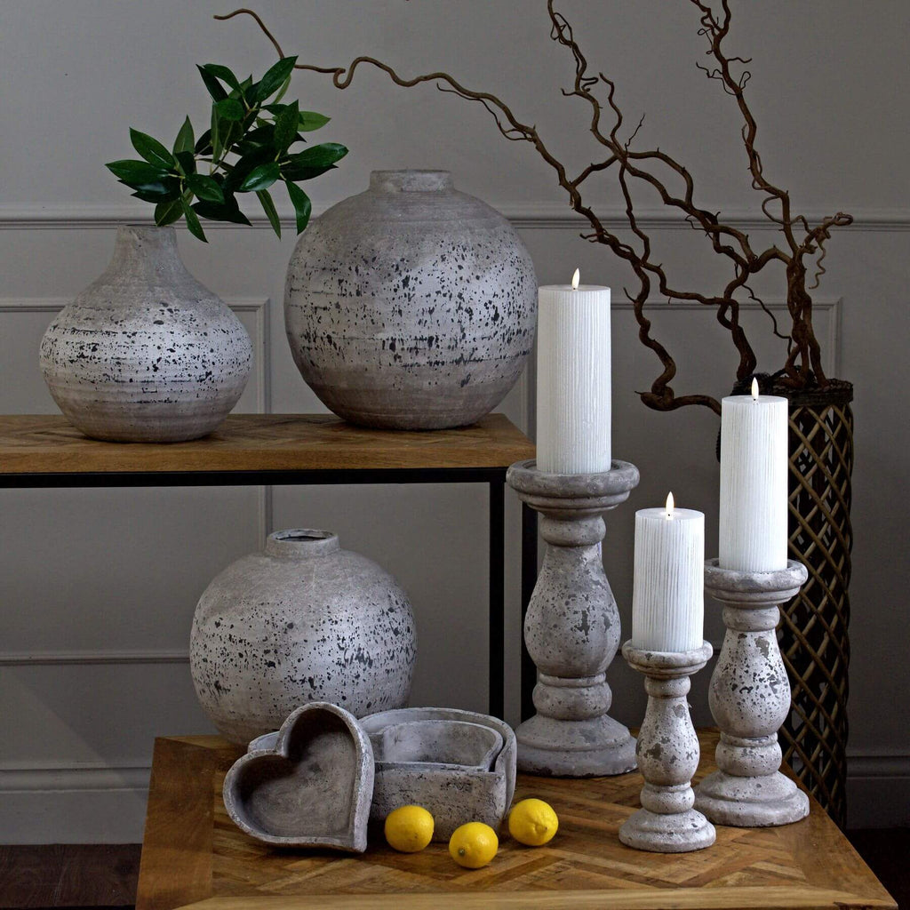 a soft-lit stack of three natural stoneware dishes on a rustic wooden table