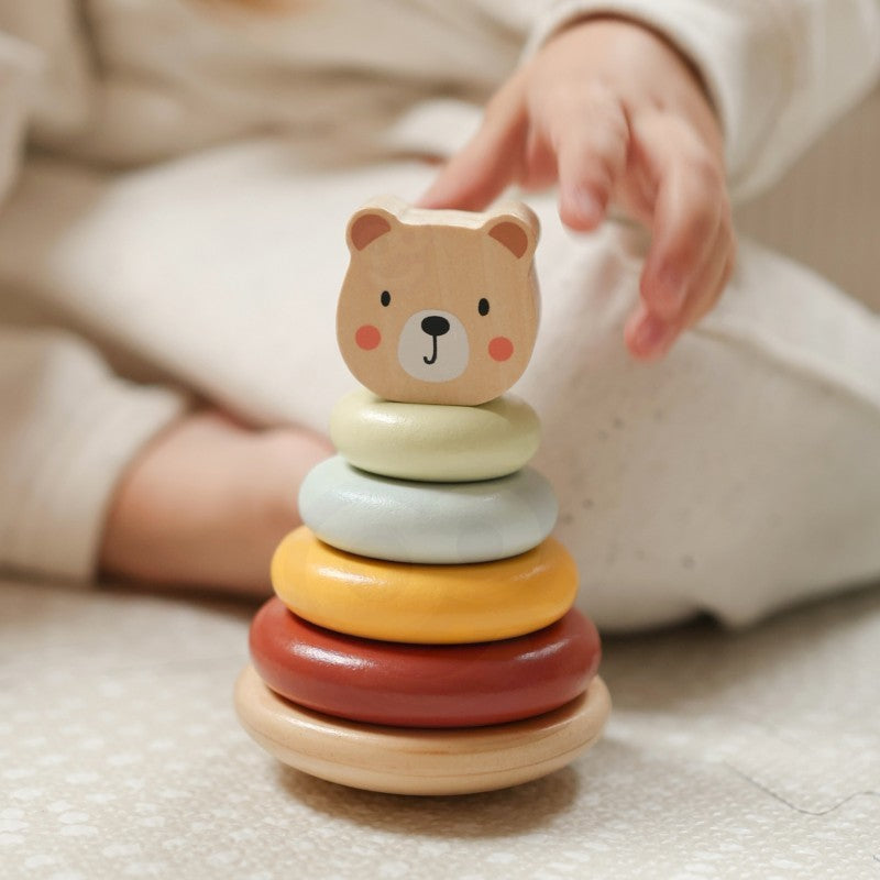 a child's hand pulling the wooden elephant toy on wheels across a sunlit floor