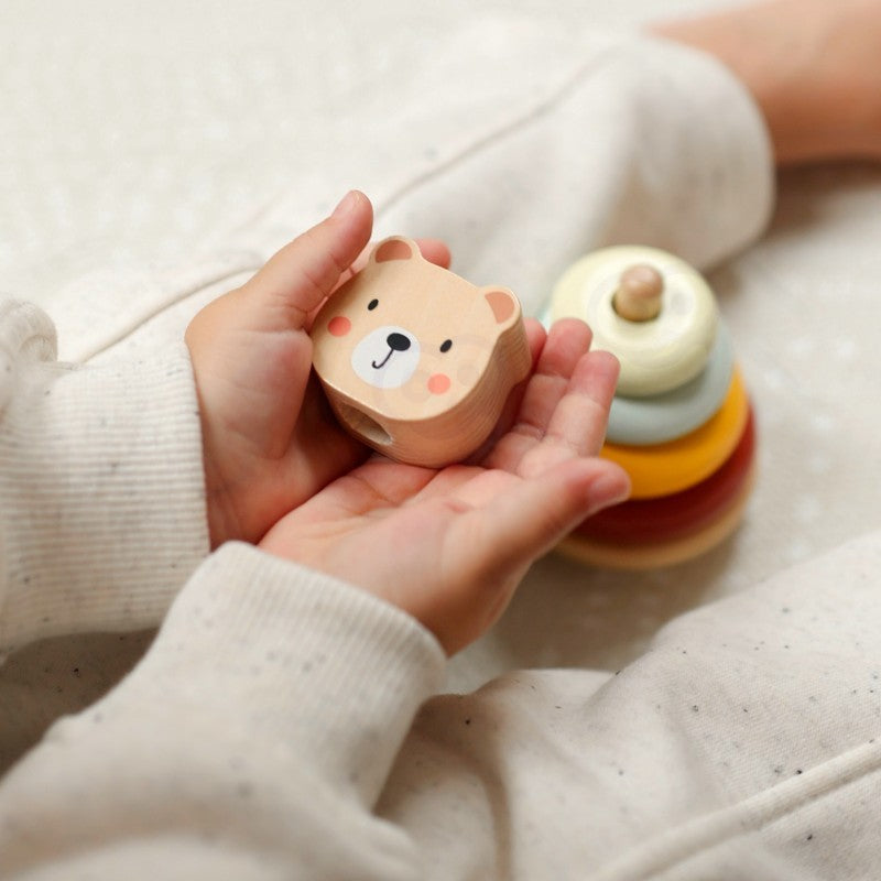 a child's hand pulling the wooden elephant toy on wheels across a natural wood floor