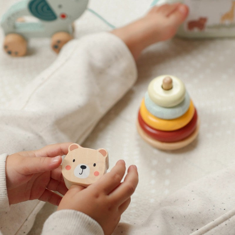 a child's hand pushing the wooden elephant toy from the 3in1 set across a natural wood floor