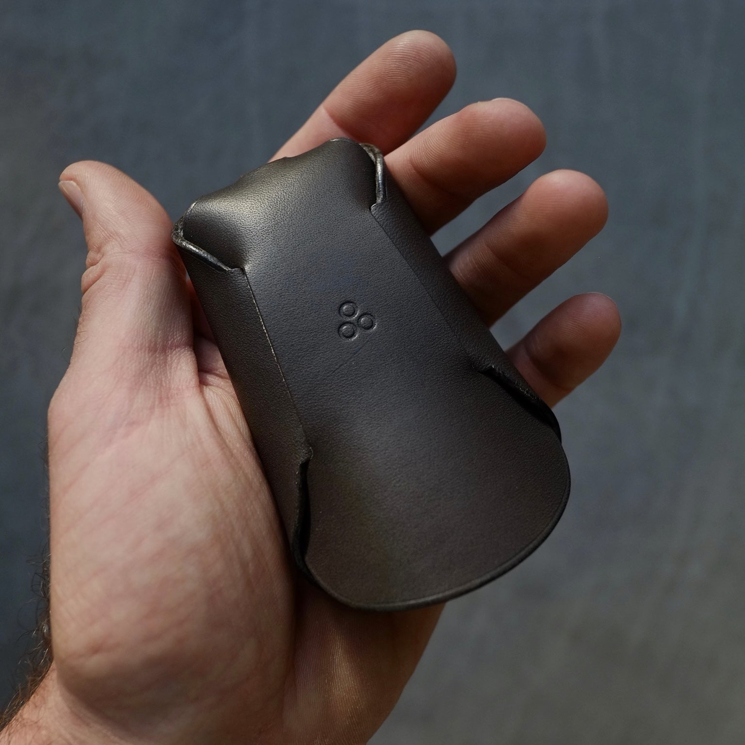 softly lit black leather keyholder lying open on a cozy fabric, revealing its folded construction