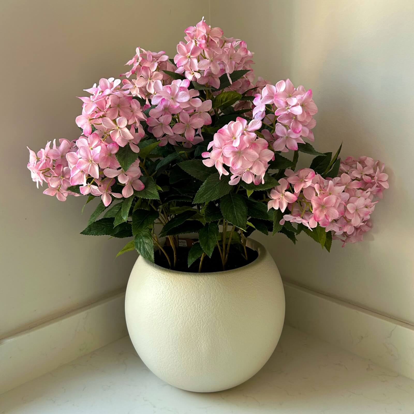 Large pink faux hydrangea plant in pot, soft romantic blooms, lifelike artificial flowers, ready-to-display home decor centerpiece by Sostter at brixbailey.com