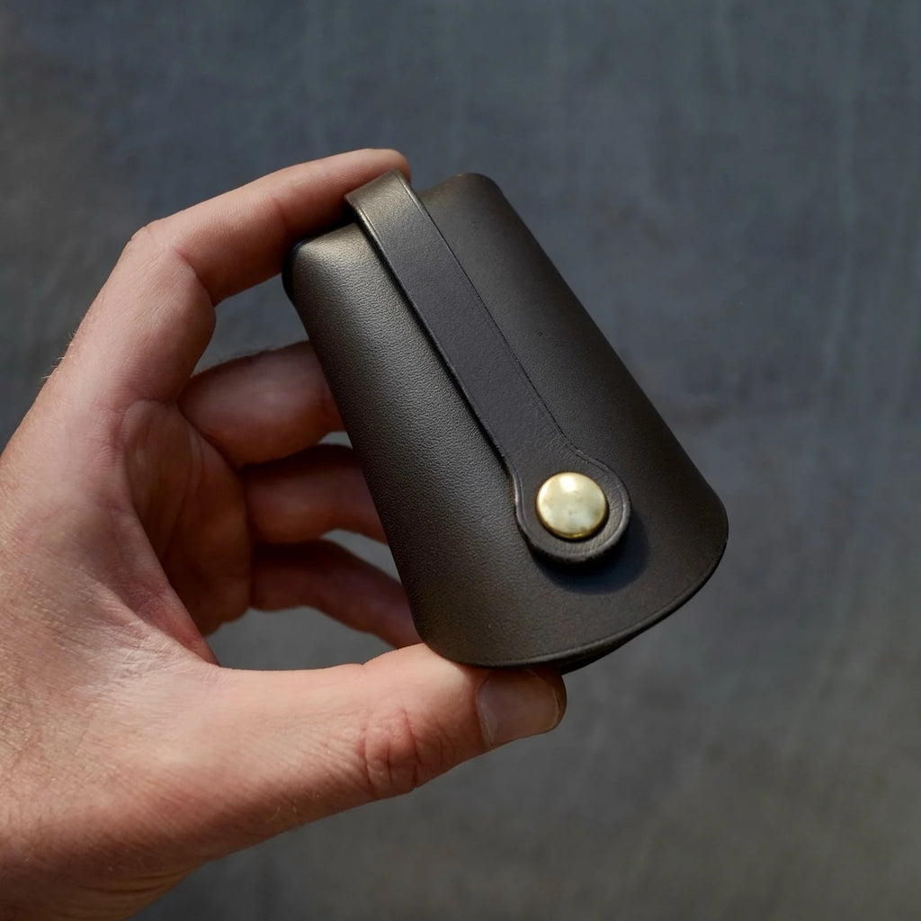 playful close-up of a black folded keyholder with keys fanned out on a sunlit wooden table
