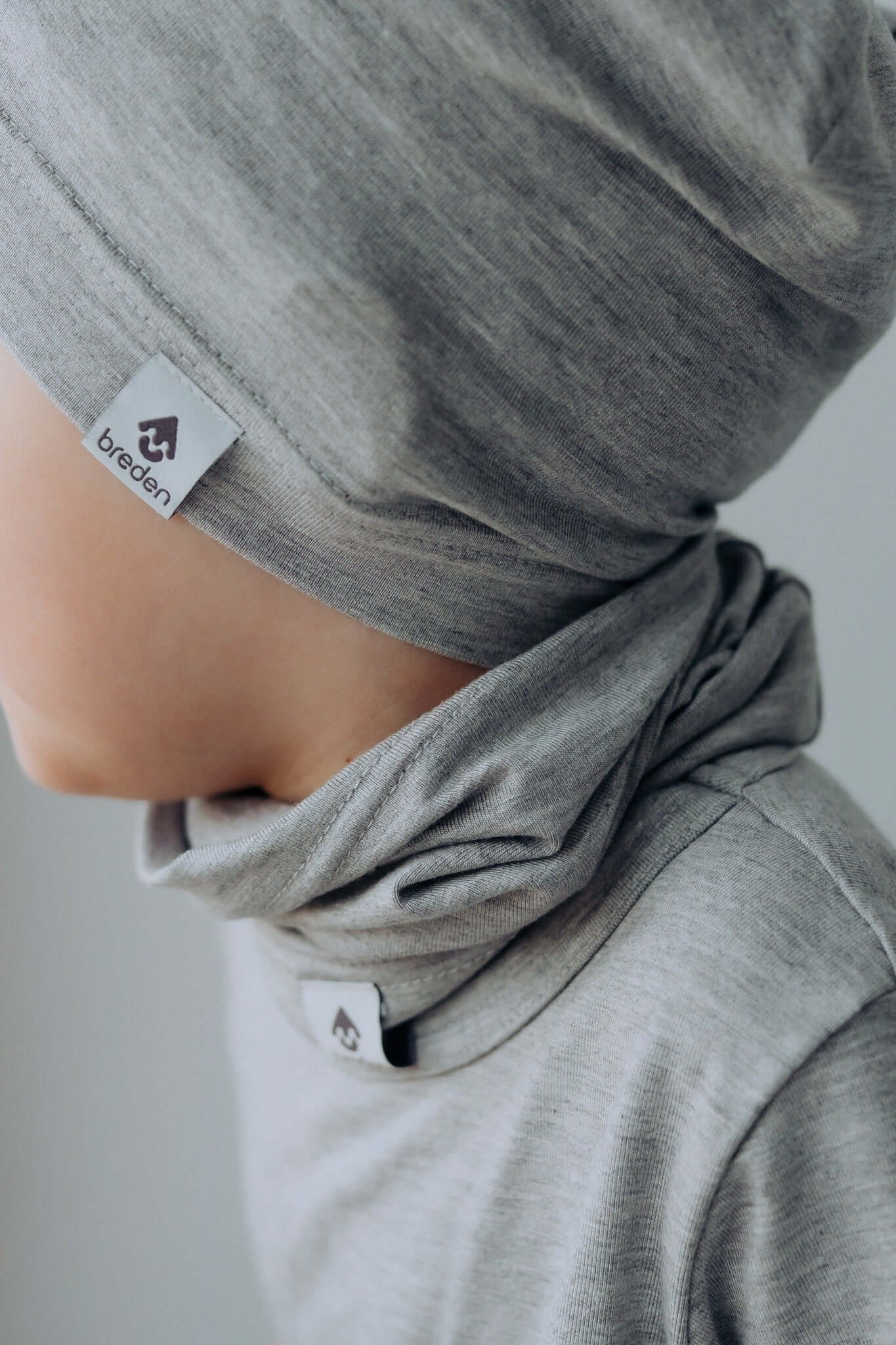 a child's hand gently holding the soft, lightweight bamboo summer scarf in a sunlit garden