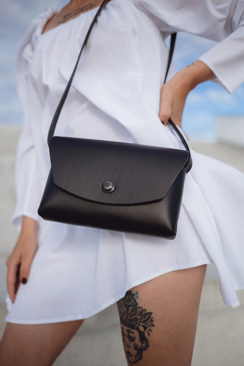 playful shot of a chic black leather clutch held against a vibrant backdrop