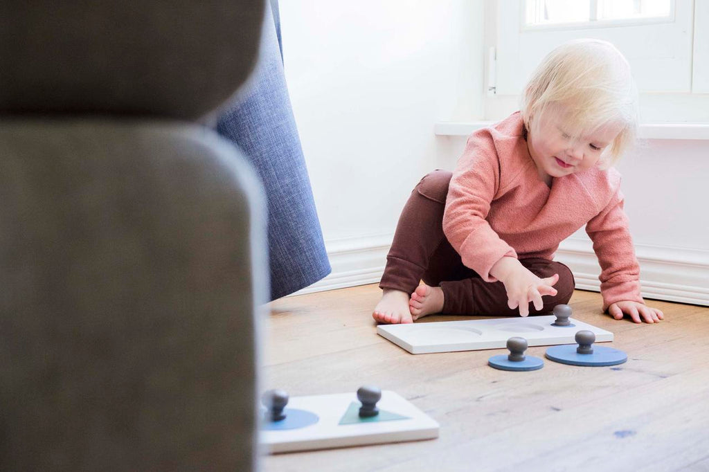 a child's hand gently placing the smallest yellow circle into its soft pine wood puzzle base