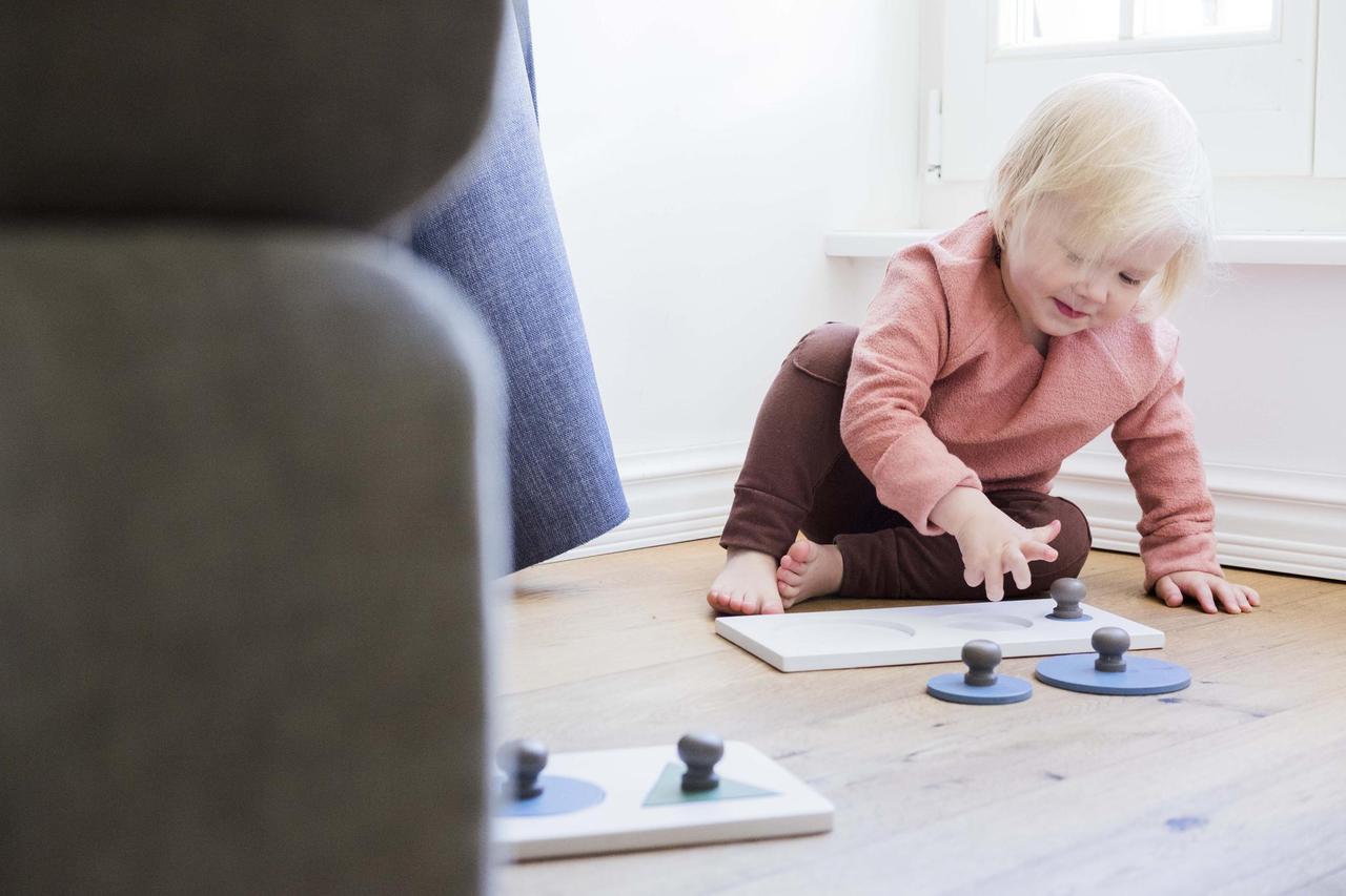 a child's hand gently placing the smallest yellow circle into its soft pine wood puzzle base