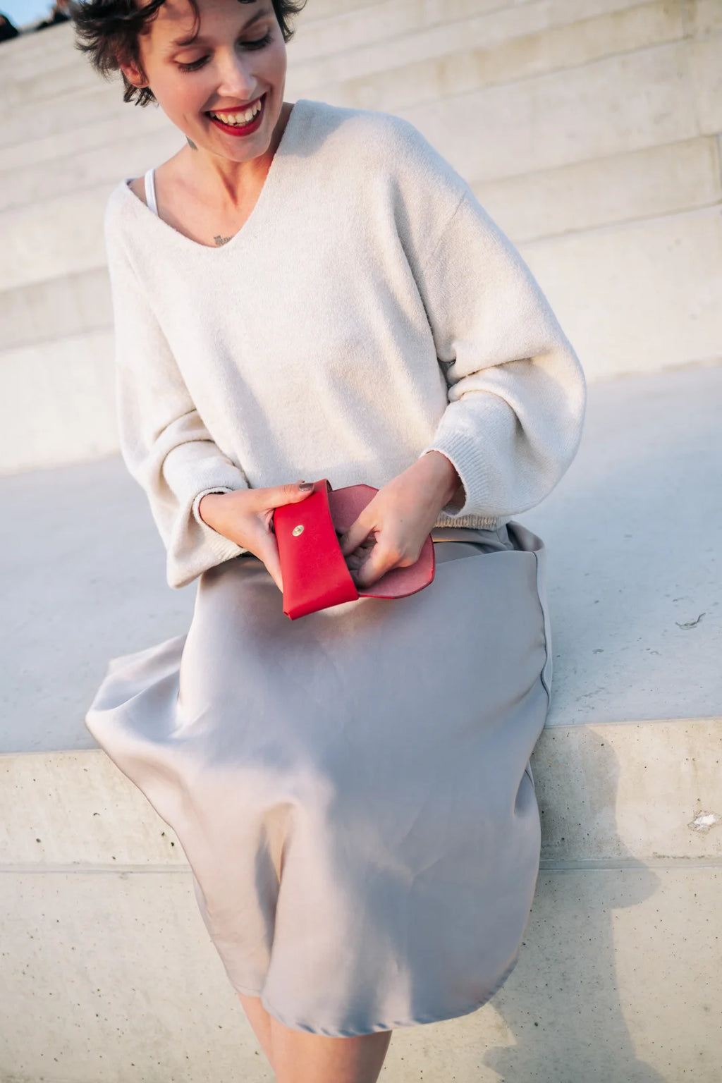 a soft, comforting close-up of a vibrant red leather sunglasses case held in someone's hand