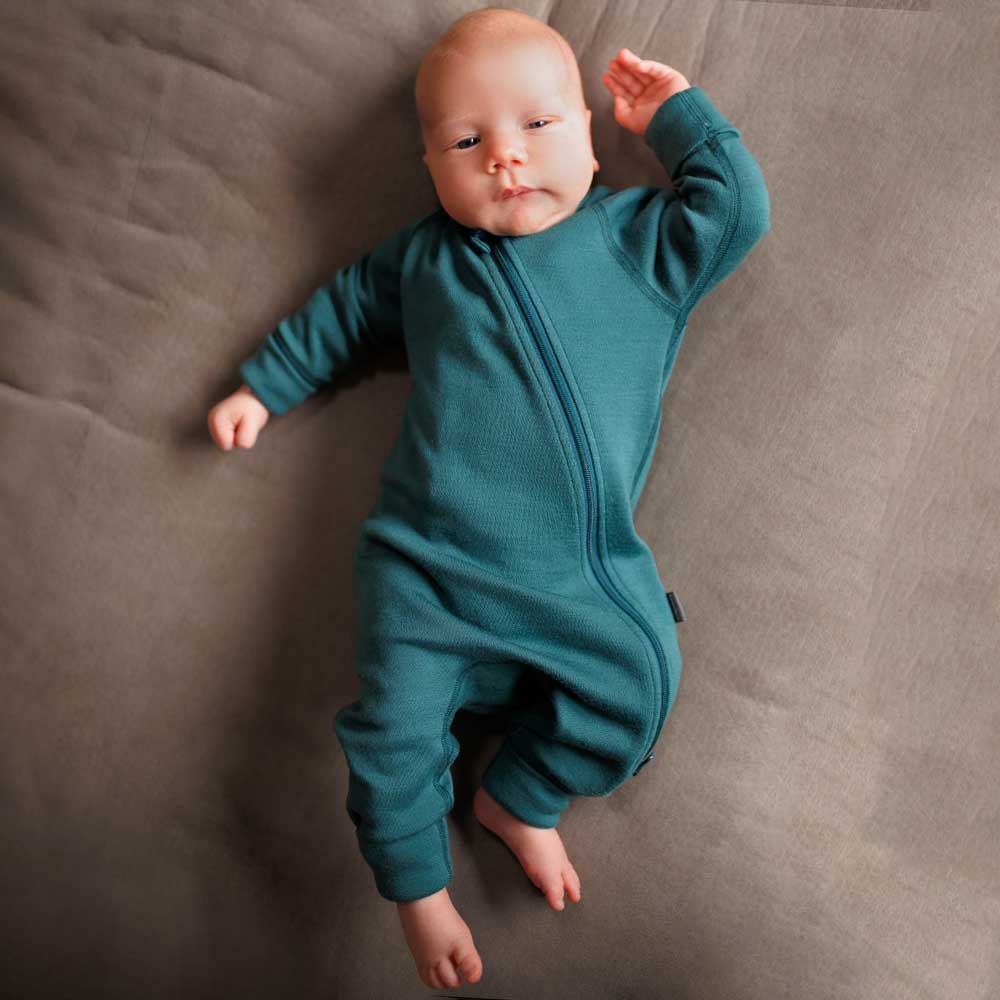a baby in a cozy merino wool jumpsuit sleeping peacefully in soft morning light