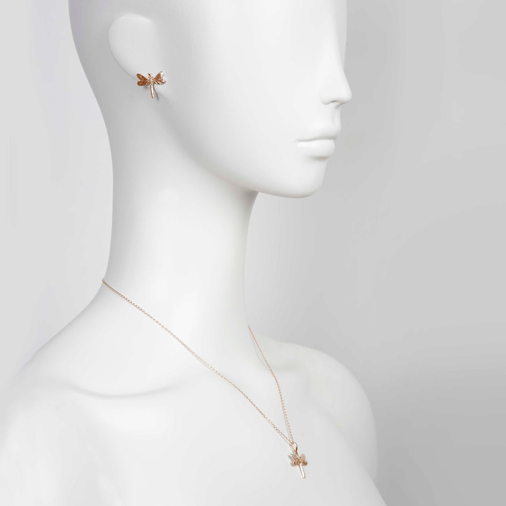 bold close-up of a rose gold dragonfly pendant with sparkling gemstones on a silver chain