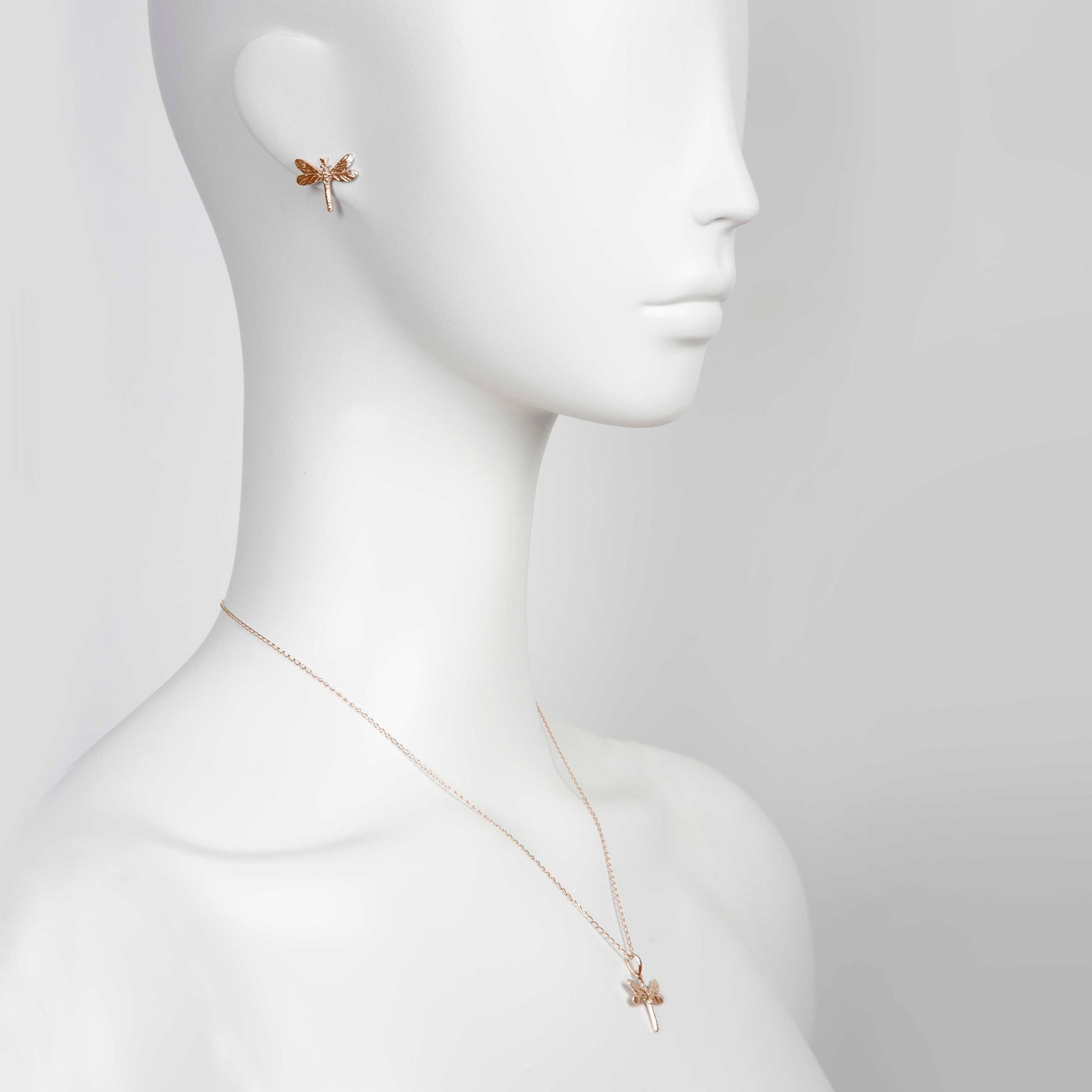 bold close-up of a rose gold dragonfly pendant with sparkling gemstones on a silver chain
