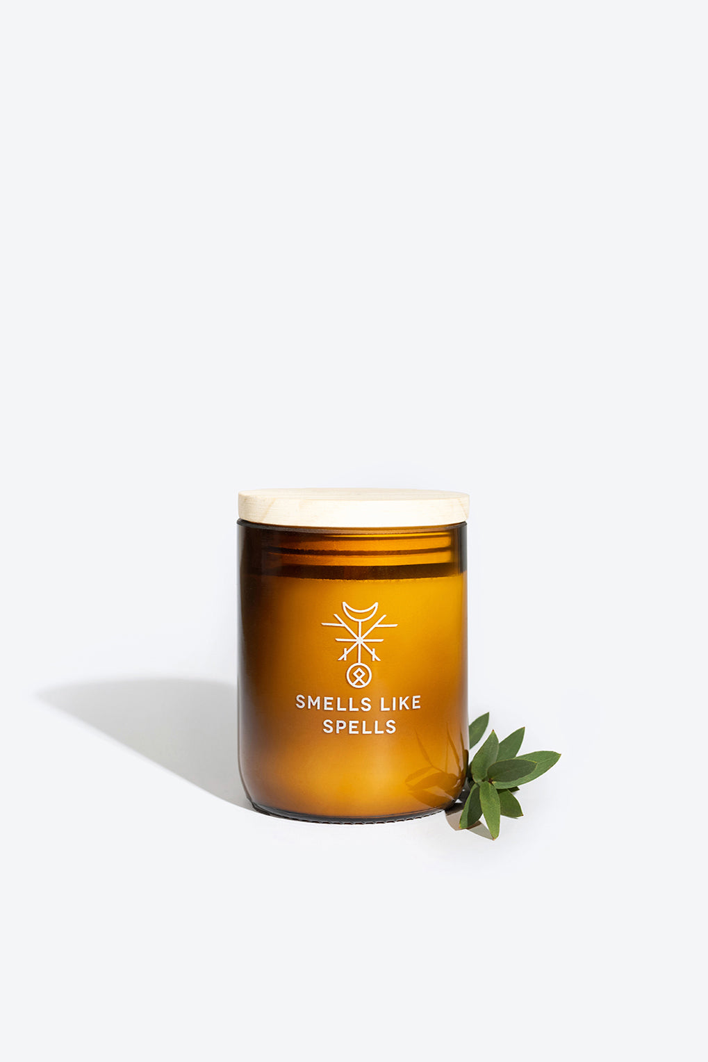 bold amber jar of eir scented candle with mint and myrrh on a dark wellness altar