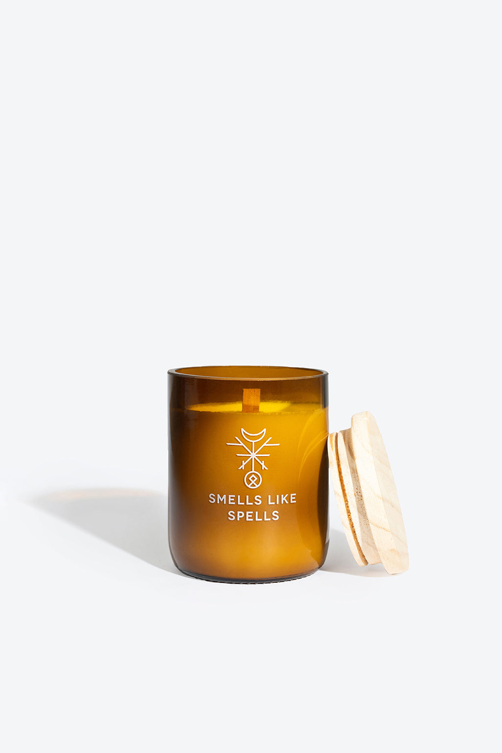 softly lit friga candle in amber glass casting a warm, cozy glow on a rustic wooden table