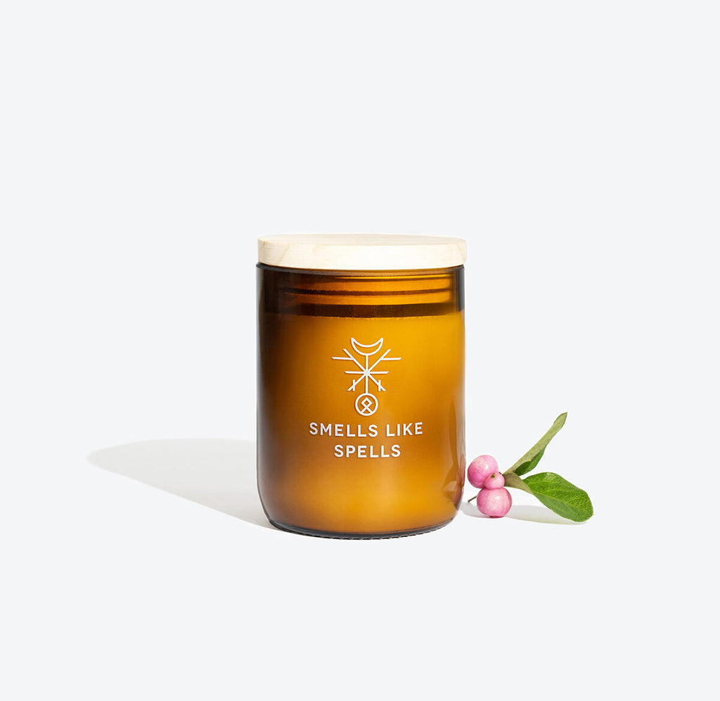 playful close-up of the idunn scented candle with its wooden wick and golden amber glass glowing
