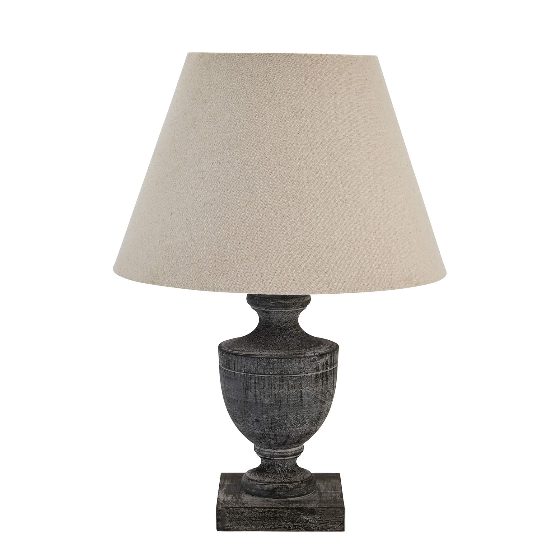 a softly lit wooden table lamp with a grey-wash patina and a cozy linen shade casting a warm glow