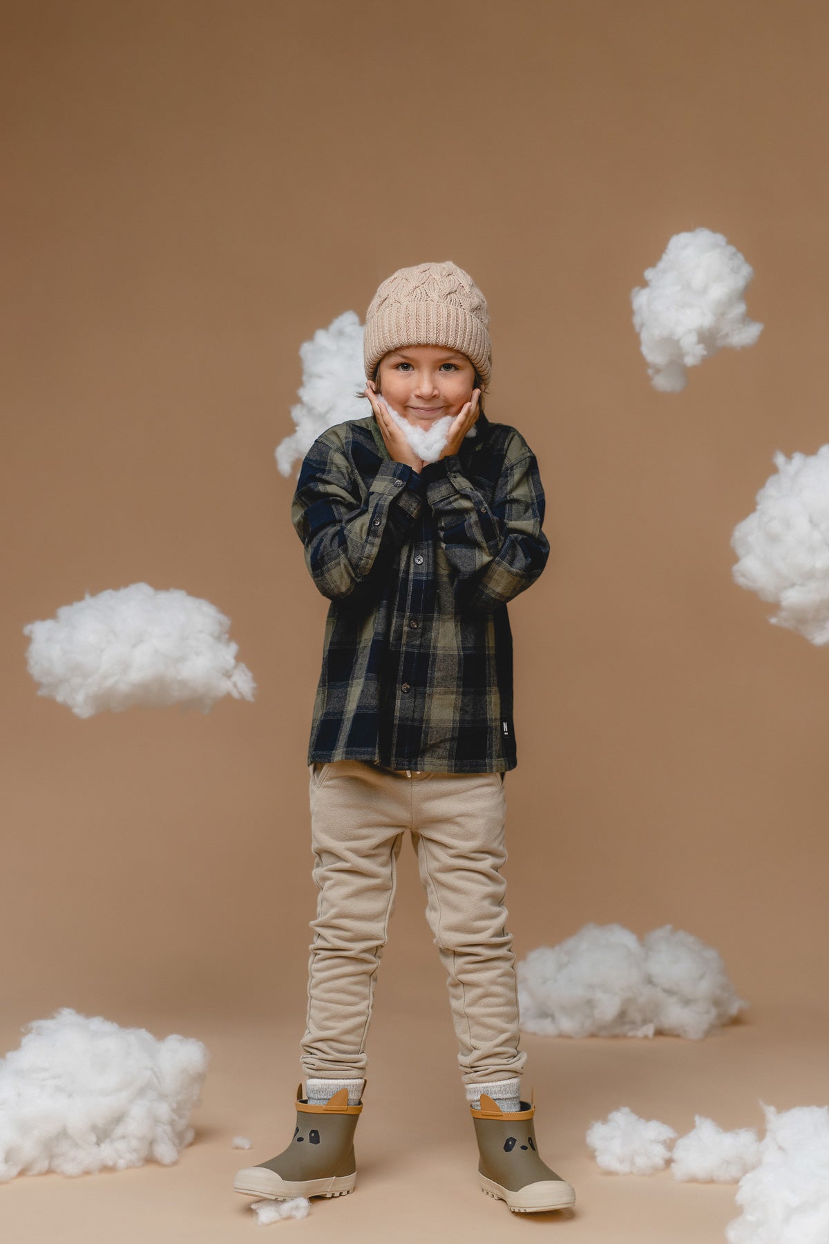 soft wheat-colored baby alpaca kids cable hat with a cozy pompom on a gentle background