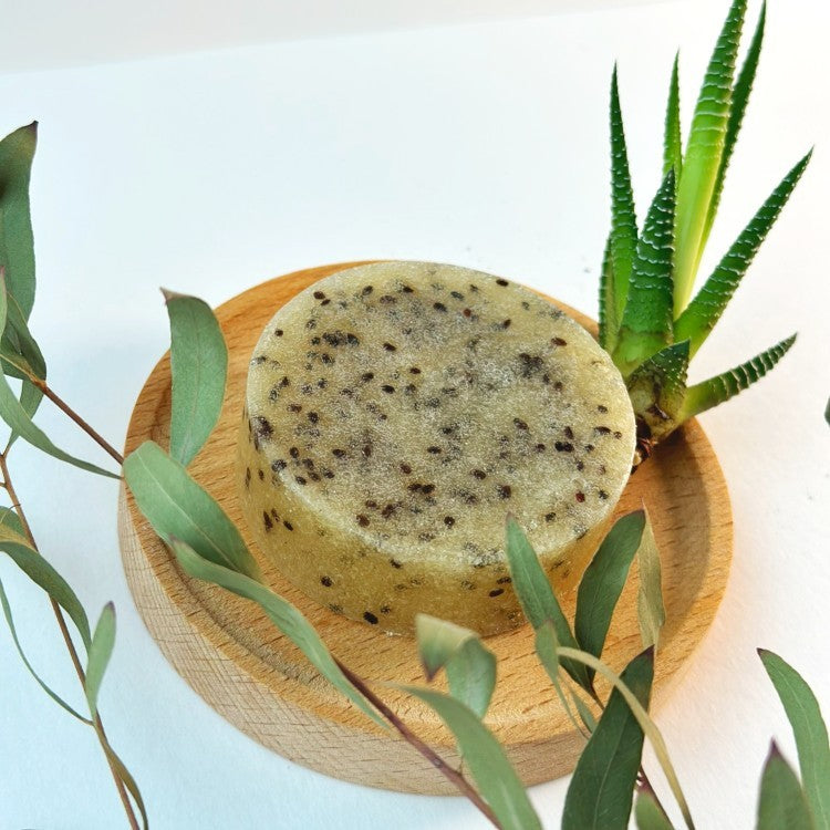 a soft-lit kiwi seed scrub bar with visible exfoliants, resting on calming natural linen
