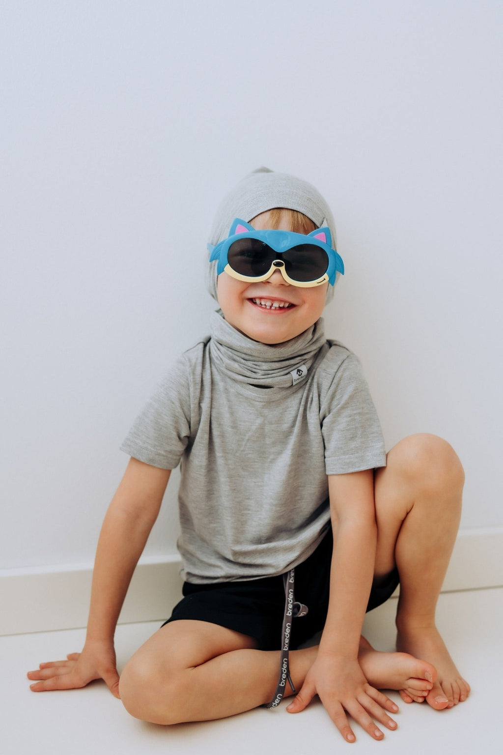 a child laughing, playfully wearing the lightweight bamboo tube-scarf like a superhero mask on a sunny day