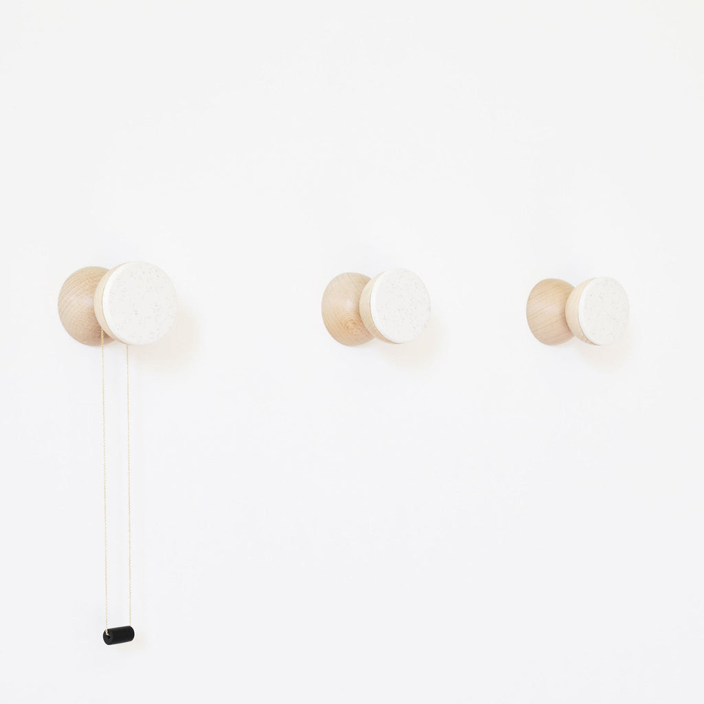 bold modern white sand ceramic and beech wood wall hook on a clean minimalist background