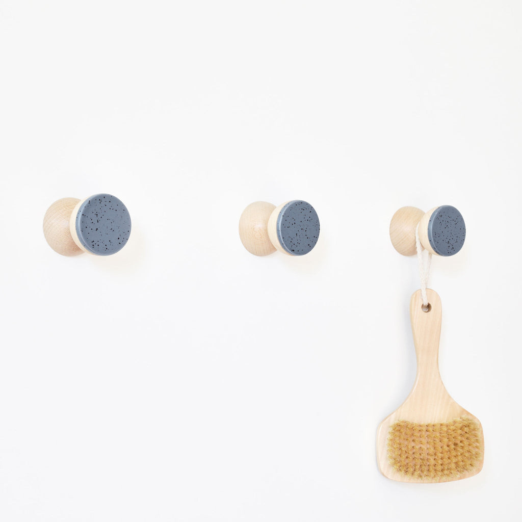 bold blue-speckled ceramic wall hook on beech wood in dramatic light