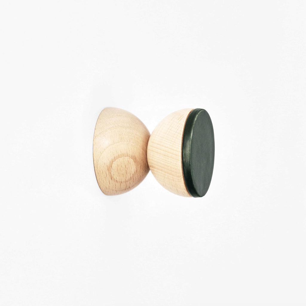 a playful dark green ceramic hook with a beech wood base holding a colorful scarf