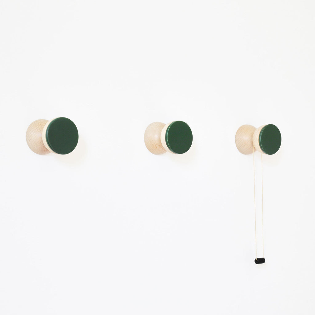 bold dark green ceramic and beech wood wall hook in dramatic close-up lighting