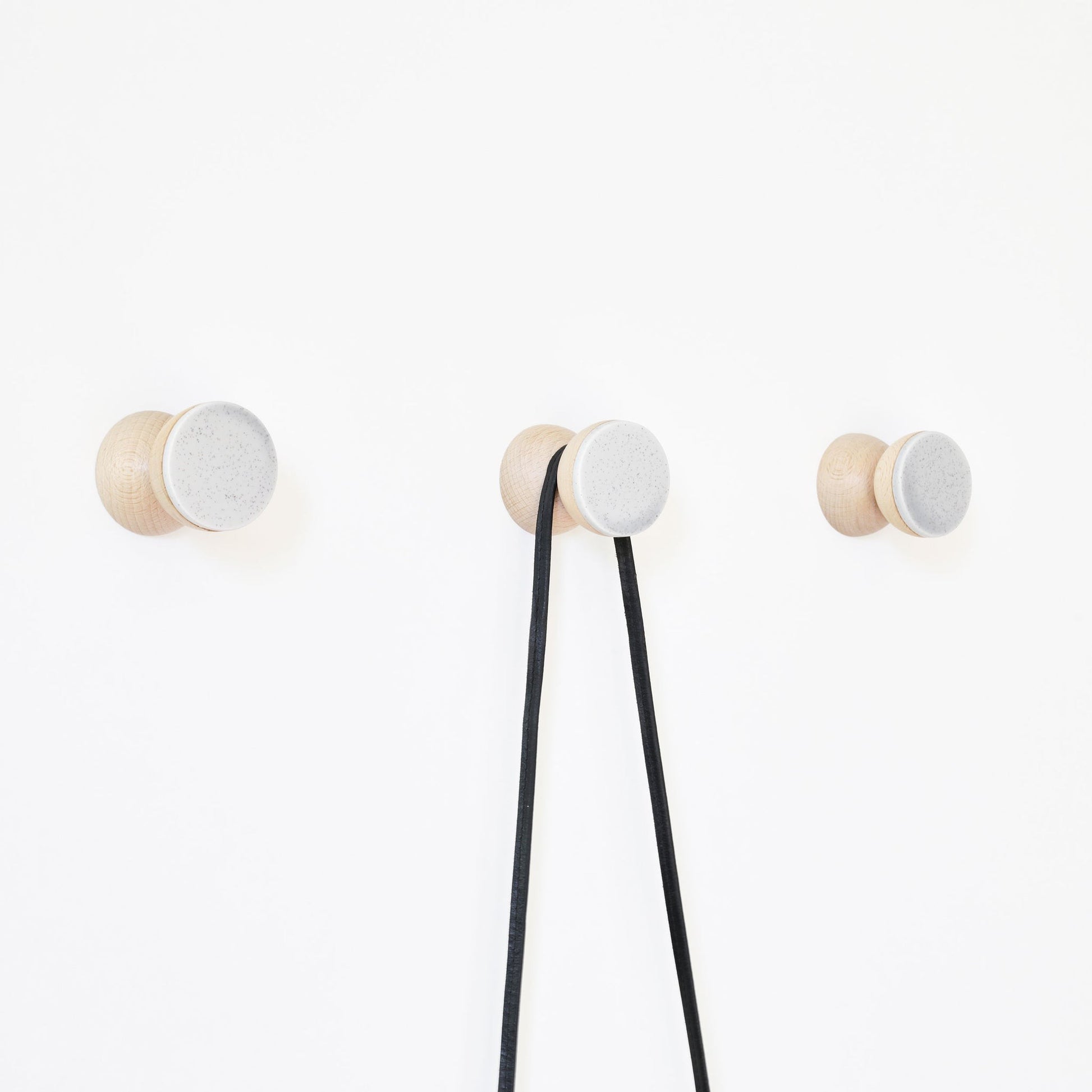 bold grey sand ceramic and beech wood wall hook in dramatic close-up lighting