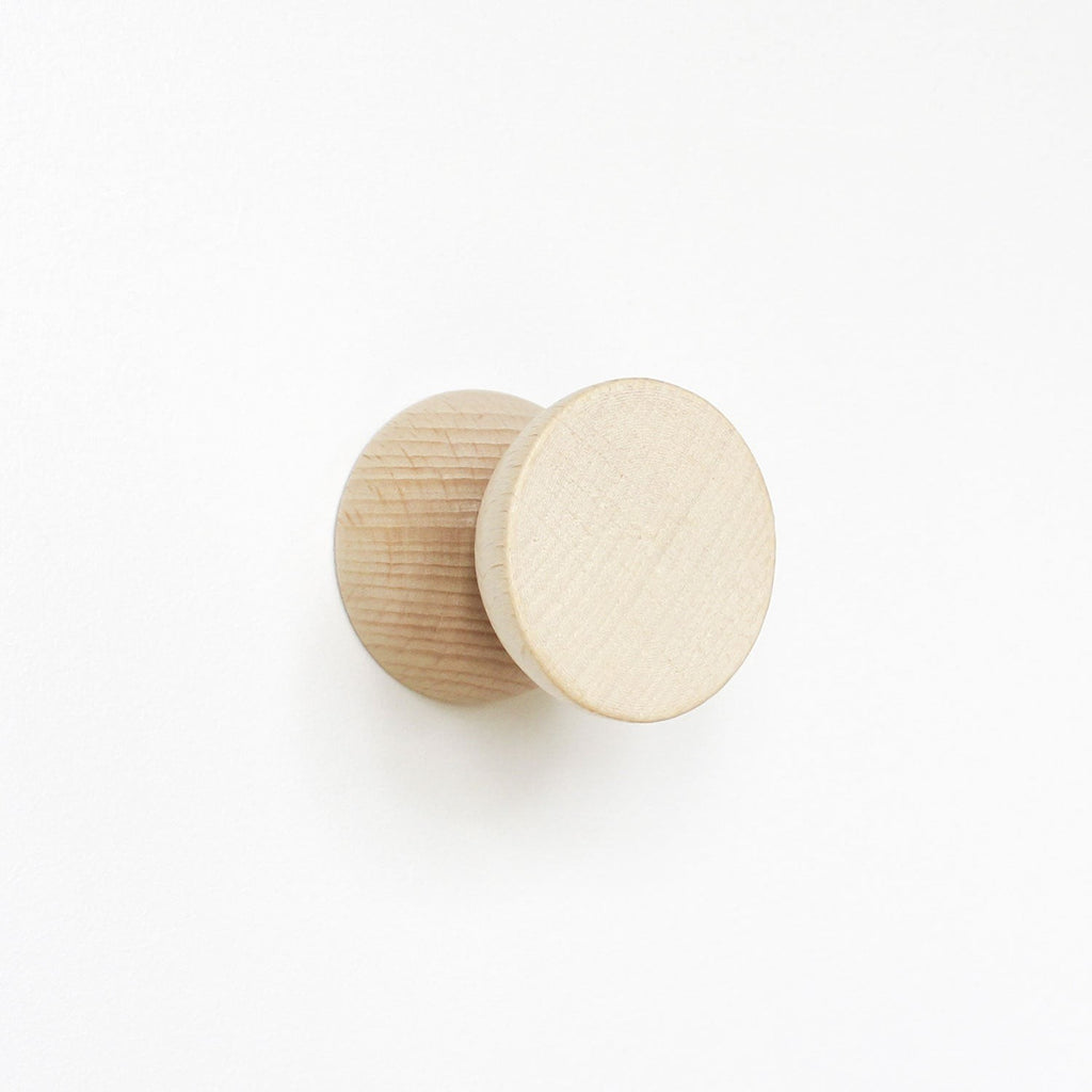 close-up of two playful beech wood wall hooks casting fun shadows on a bright background