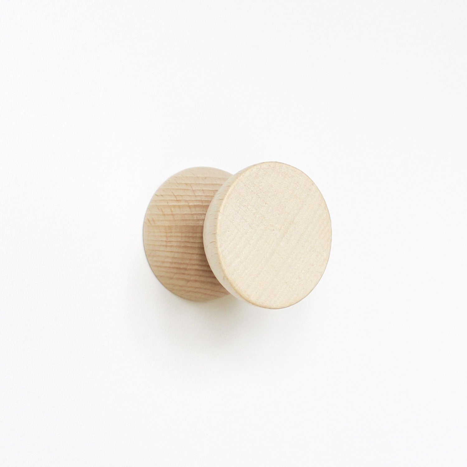 close-up of two playful beech wood wall hooks casting fun shadows on a bright background