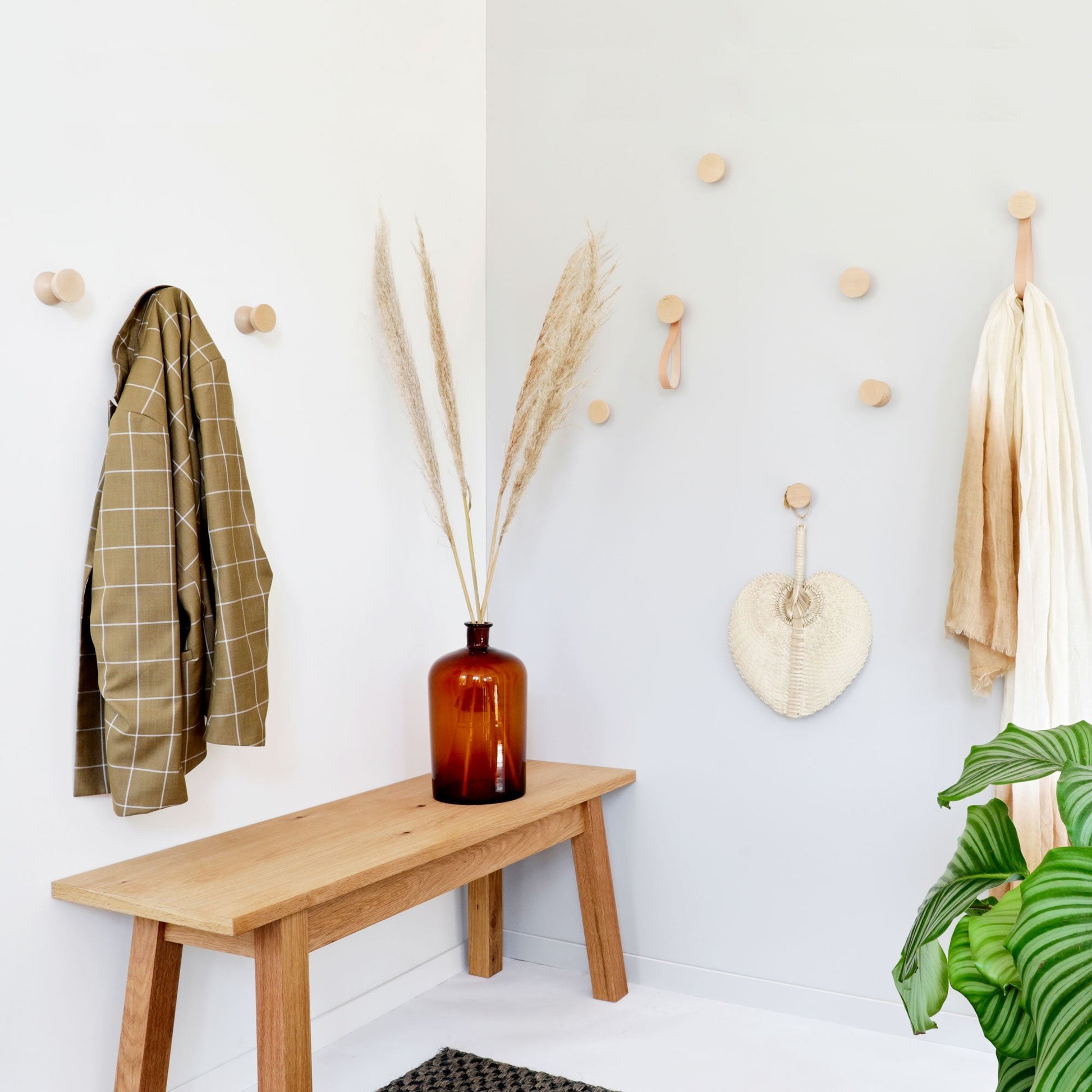 two minimalist beech wood hooks on a bright wall, showcasing their clean geometric form and warm wood grain