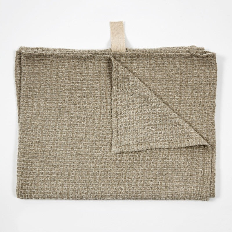 a playful grey linen bath towel draped casually, showing off its textured weave