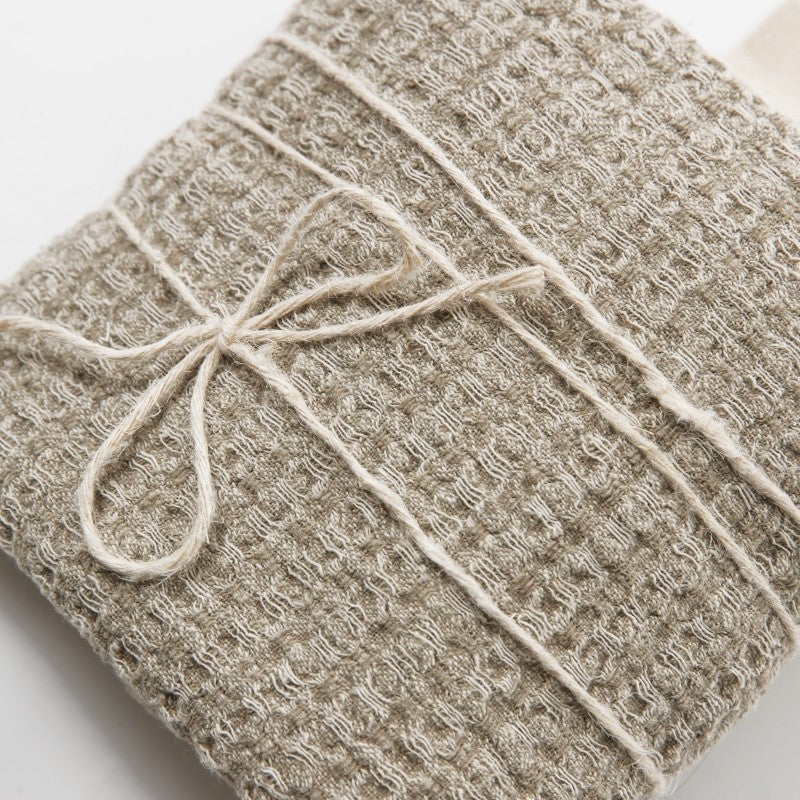 a functional oversized grey linen towel hanging from a simple wooden hook