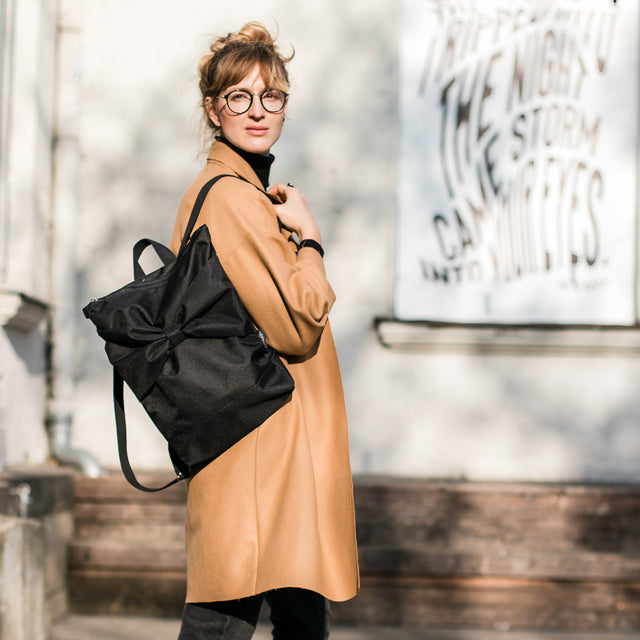 Chic Black Bow Backpack – Elegant & Weather-Resistant by Muni at www.brixbailey.com