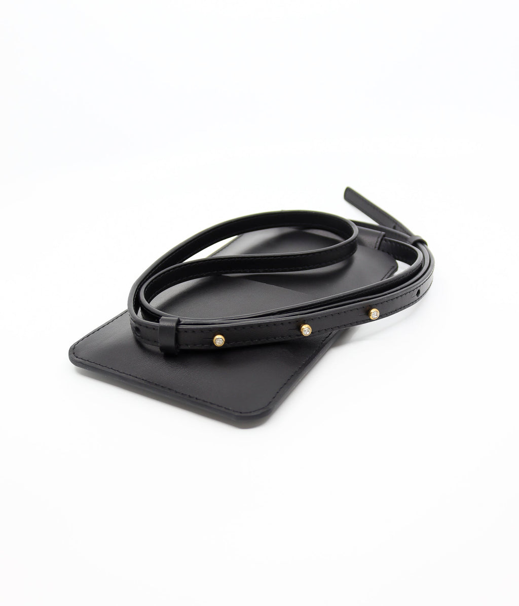 playful black leather crossbody phone bag with gold buttons, worn over a denim jacket