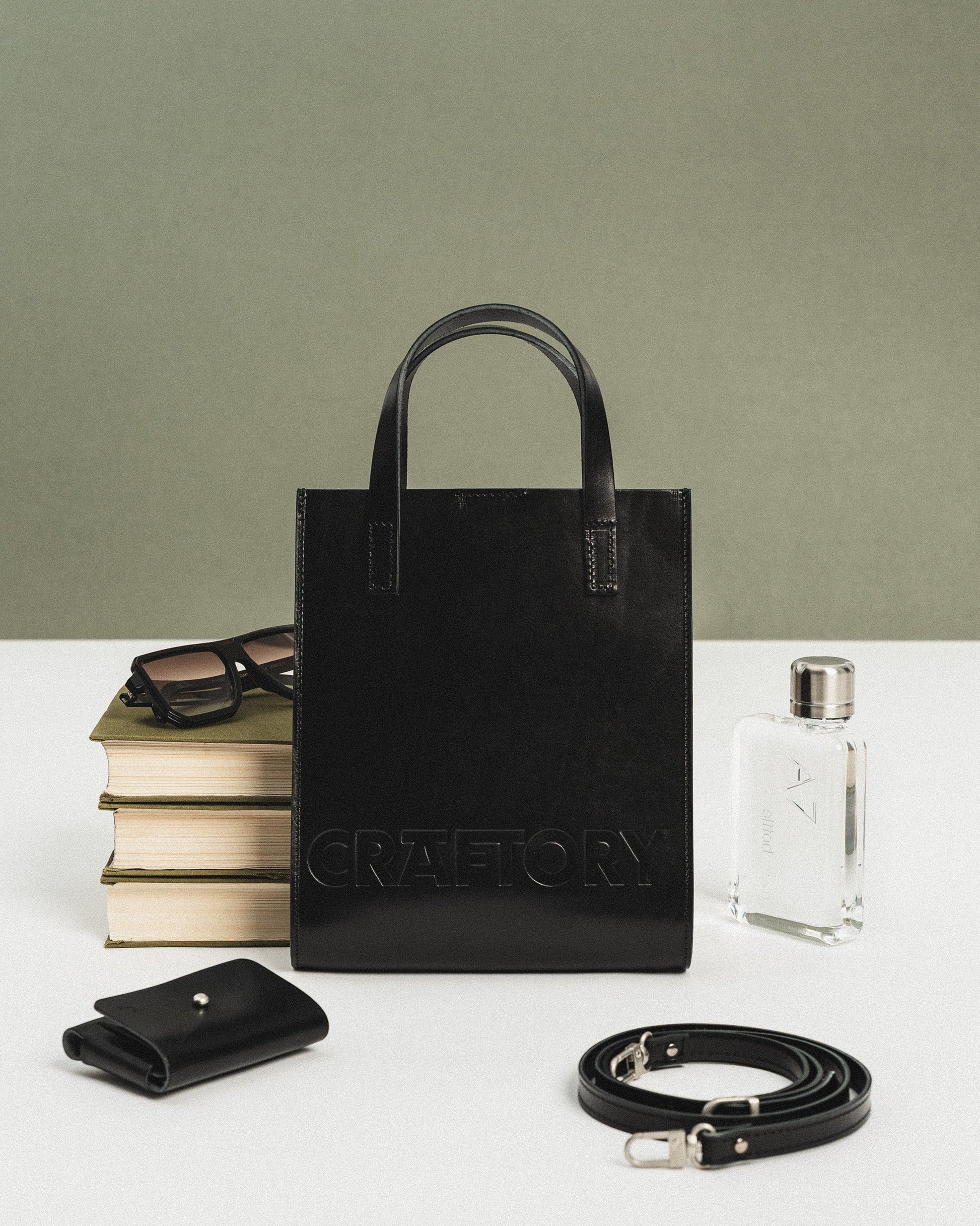 a confident woman holding a chic black leather bucket bag against a modern urban backdrop