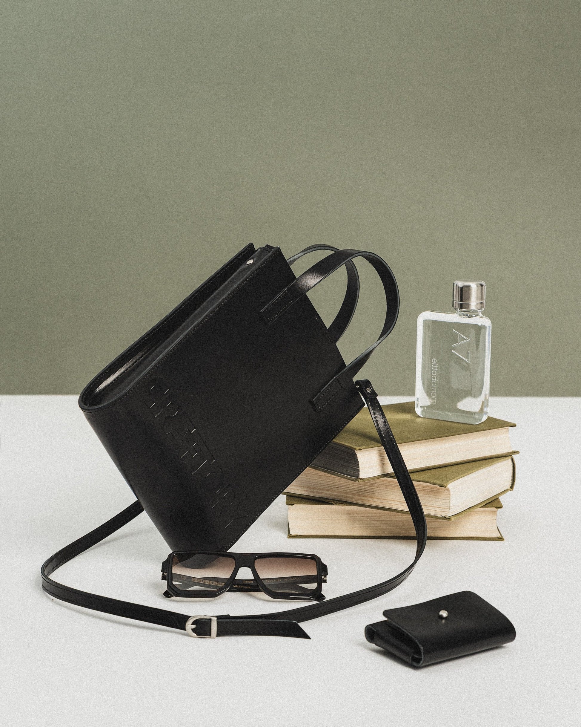 black bucket handbag with adjustable strap shown open on a table