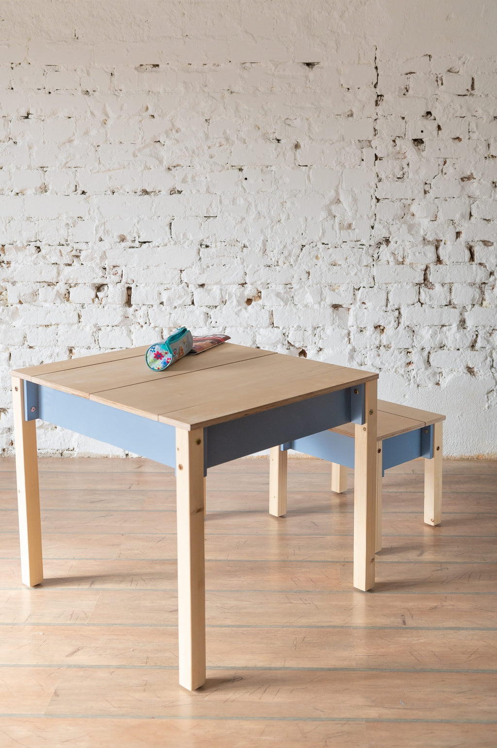 a child's compact birch wood table and chair set with storage, shown in a warm morning light