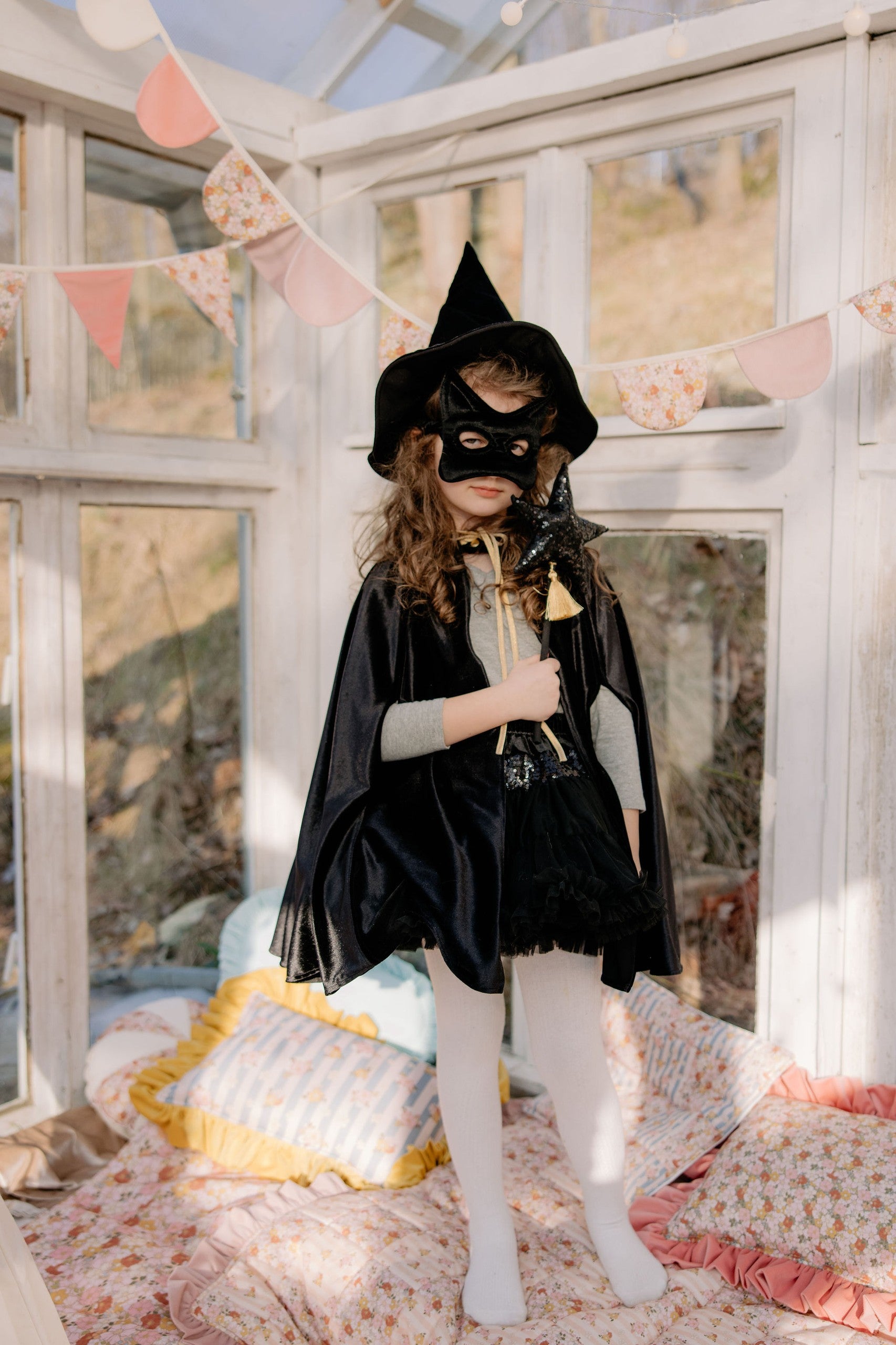 playful child wearing a sparkling black cat mask with sequins that shimmer in soft afternoon light