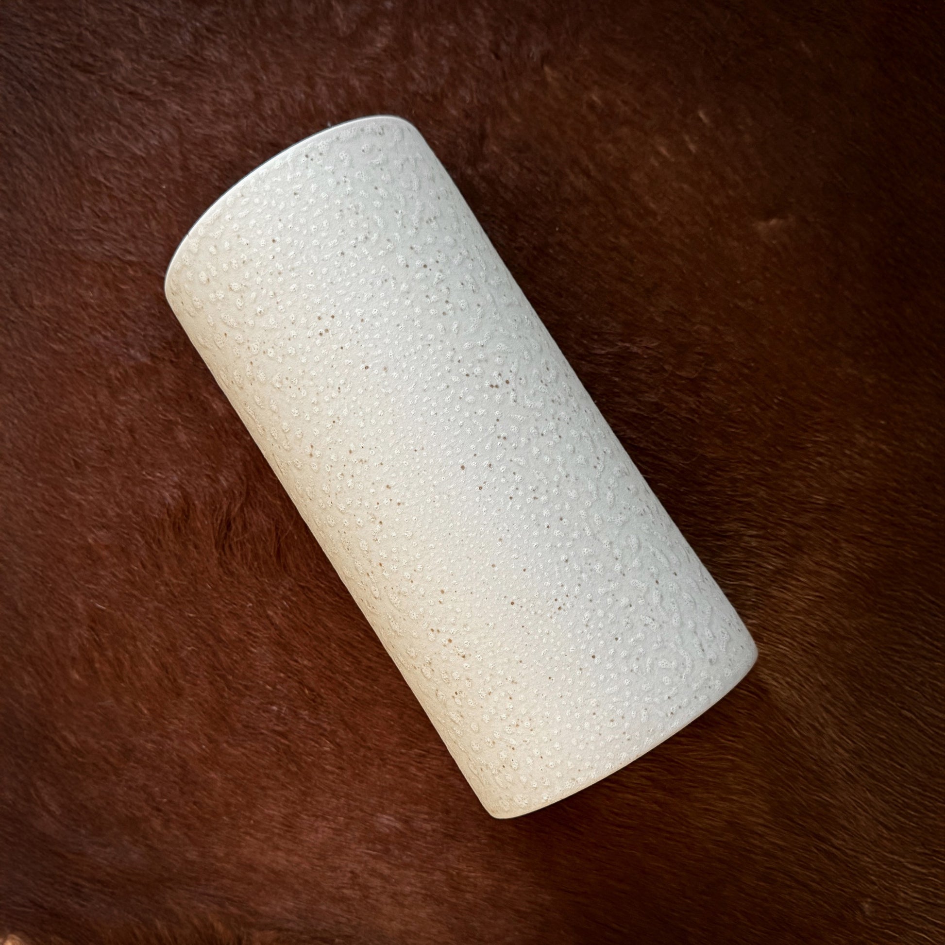 a playful beige ceramic wall light with brown speckles casting a fun, dappled glow