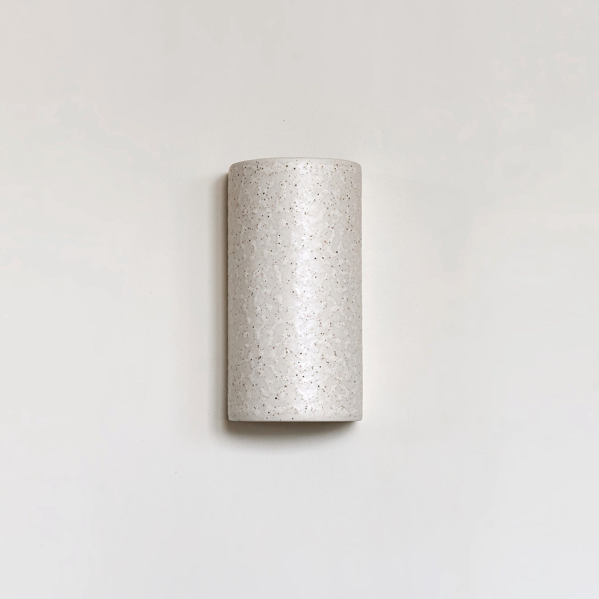 elegant beige ceramic wall light with a refined spotted brown glaze, casting a soft glow