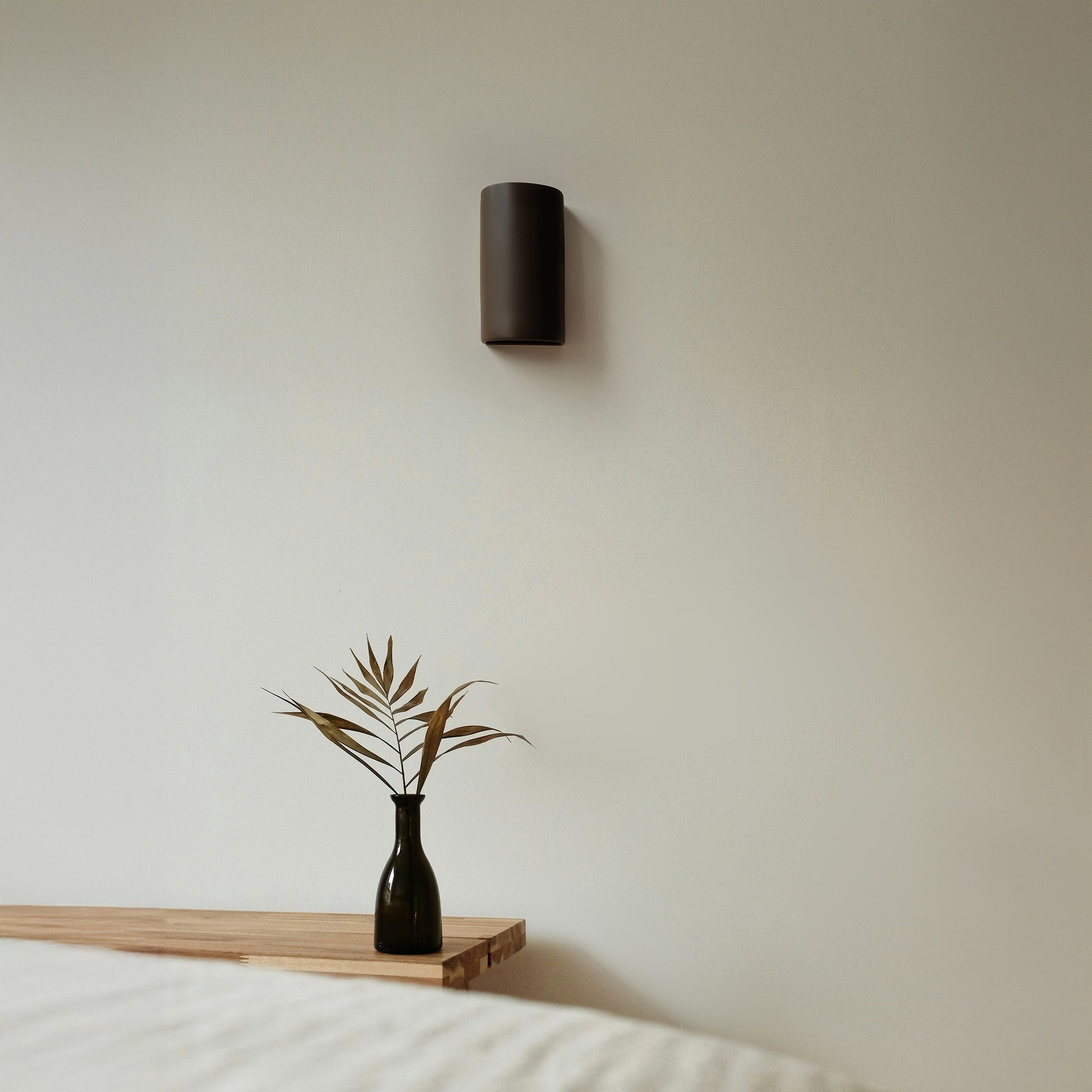 a soft brown ceramic wall light casting a warm, cozy glow in a gentle nursery setting