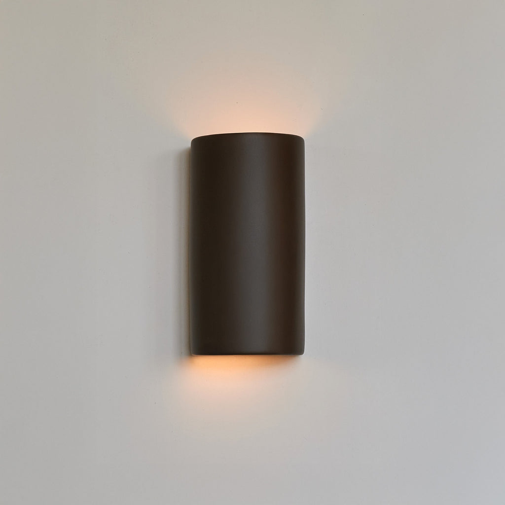 bold statement of a handcrafted warm brown ceramic wall light casting a dramatic, sculptural shadow