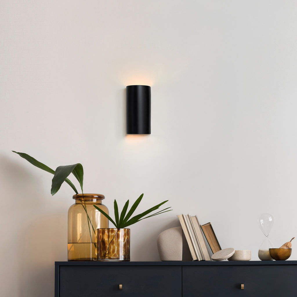 a softly glowing black ceramic wall light casting a warm, cinematic glow in a cozy nursery