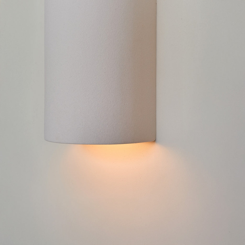 a softly glowing matte white ceramic wall light casting a warm, comforting glow in a nursery