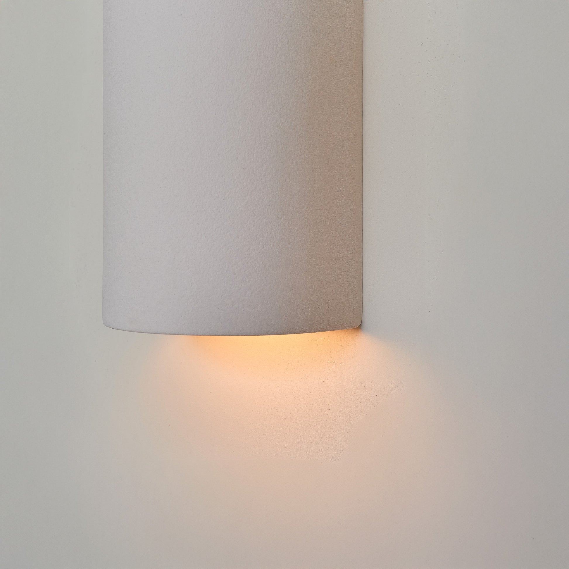 a softly glowing matte white ceramic wall light casting a warm, comforting glow in a nursery